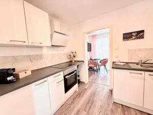 a kitchen with white cabinets and black counter tops at Stilvolles Apartment mit Balkon - zentrumsnah, self checkin in Augsburg
