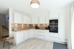 a white kitchen with white cabinets and a staircase at Chalet Aineck Snowwhite in Sankt Margarethen im Lungau