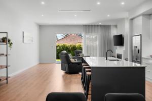 a kitchen and living room with a counter and chairs at Belle Escapes - Henley Beach House in Henley Beach