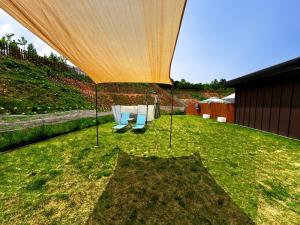 a table and chairs under a large tent in a yard at Dangjin Dogpelis Glamping in Dangjin