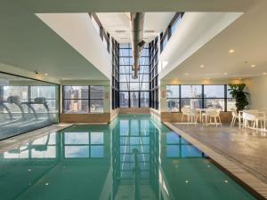 a swimming pool in a building with tables and chairs at Mercure Sydney in Sydney