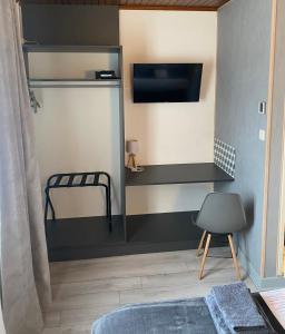 a room with a bed and a tv and a chair at Auberge de Lamagistere in Lamagistère