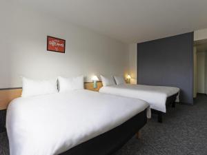 Una habitación de hotel con dos camas y un cartel en la pared. en ibis Paris Pantin Eglise, en Pantin 38 fotos más