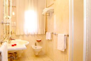 a white bathroom with a sink and a toilet at Hotel Ariston in Marina di Grosseto