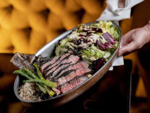 a person holding a tray of meat and a salad at Pullman Sao Paulo Ibirapuera in Sao Paulo