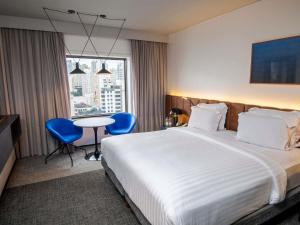 a hotel room with a bed and a table and chairs at Pullman Sao Paulo Ibirapuera in Sao Paulo
