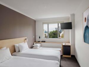 Dos camas en una habitación de hotel con ventana. en ibis Sydney Olympic Park, en Sídney 70 fotos más
