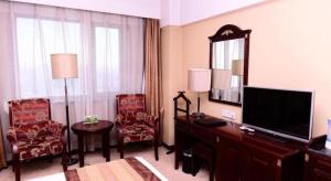 a hotel room with a television and a desk and chairs at Heilongjiang Kunlun Hotel in Harbin