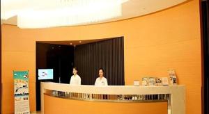 two people standing behind a counter in a restaurant at Jinjiang Inn Dalian Development Zone Jinma Road Light Railway Station in Jinzhou