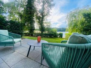 a patio with three chairs and a table and a lake at Landhaus am See - Gästezimmer in Strausberg