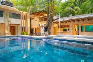 Una familia parada frente a una casa con piscina. en Dreamcatcher Luxury, en Santa Teresa Beach