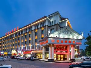 a large building on a street with cars parked in a parking lot at Vienna Hotel Tianjin Huaming in Tianjin