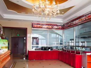 a restaurant with a red counter and a chandelier at Vienna Hotel Tianjin Huaming in Tianjin