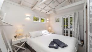a white bedroom with a bed and a window at 'The Pelicans Nest at Pretty Beach' by HolidayCo in Pretty Beach