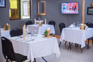 a dining room with two tables with white table cloth at Arusha Giraffe Lodge in Arusha