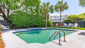 a swimming pool in a yard with chairs and trees at 3800 Cameron Boulevard AvantStay Pool Ocean Views Deck in Isle of Palms