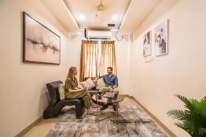 a man and woman sitting on a couch in a living room at FabHotel Prime Royal Castle - Nr Coimbatore North Railway Station in Coimbatore
