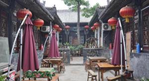 a patio with tables and red umbrellas in a building at Pingyao Yufengheng Hotel in Pingyao