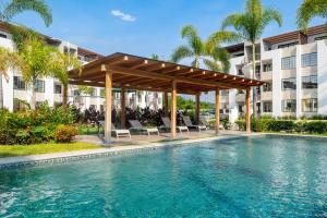 a swimming pool with a pergola next to a building at Departamento en condominio con alberca excelente ubicación in Manzanillo