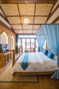a large bedroom with a large bed with blue drapes at Lijiang Yue Tu Inn in Lijiang