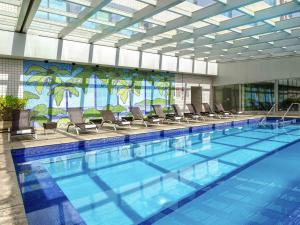 a large swimming pool with chairs in a building at Novotel Sao Paulo Center Norte in Sao Paulo