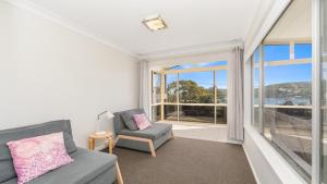 a living room with a couch and a chair at 'Horizons On Heath' by HolidayCo in Hardys Bay