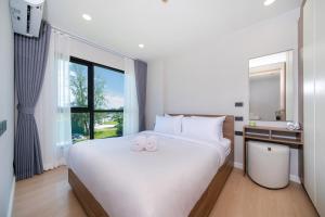 a bedroom with a large white bed and a window at Brand new 1 BR apt 403 at Space Condo near Boat Avenue in Ban Thalat Choeng Thale +24 photos