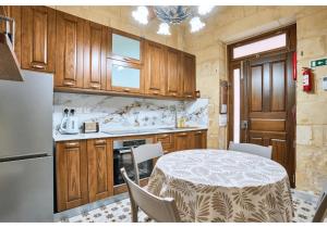 una cocina con una mesa y un refrigerador en Birgu's central traditional apartment, en Birgu