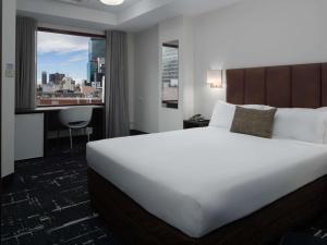 メルボルンにあるメルキュール ウェルカム メルボルンのベッドと机と窓のあるホテルの部屋