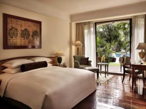 a bedroom with a large white bed and a living room at Sofitel Angkor Phokeethra Golf & Spa Resort in Siem Reap