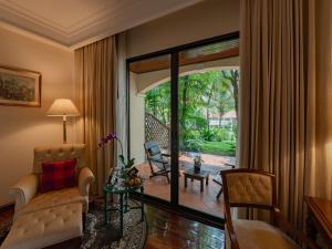 a living room with a couch and a chair and a sliding glass door at Sofitel Angkor Phokeethra Golf & Spa Resort in Siem Reap +162 photos