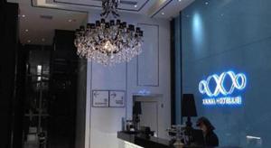 a woman sitting at a bar in a room with a chandelier at Xana Hotelle XiAn Gig Wild Goose Pagoda Branch in Xi'an