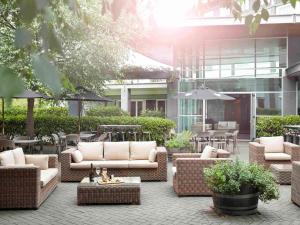 a patio with wicker couches and tables and a building at Novotel Auckland Ellerslie in Auckland