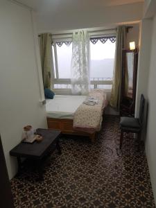 a bedroom with a bed and a window with a chair at Mannata Homesaty in Darjeeling