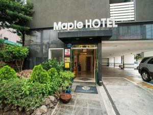 a hotel with a sign on the front of a building at Jeju Maple Hotel in Jeju