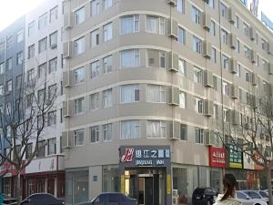un edificio alto con una mujer caminando delante de él en Jinjiang Inn Qingdao Development Zone Jinggangshan Rd., en Huangdao