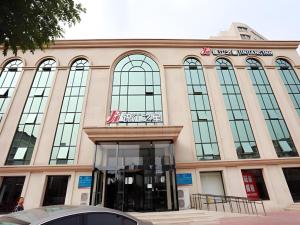 duży budynek ze szklanymi oknami wychodzącymi na ulicę w obiekcie Jinjiang Inn Hotel Tianjin Xinkai Road Branch w mieście Tiencin