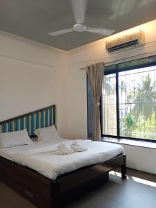 a bedroom with a bed and a large window at Alibag Beach Stay- The Grantley Hotel in Alibag
