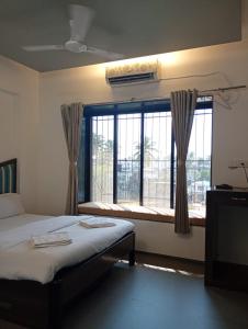 a bedroom with a bed and a large window at Alibag Beach Stay- The Grantley Hotel in Alibag