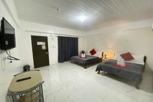een kamer met 2 bedden en een flatscreen-tv bij NGBMPC Hostel in Puerto Galera