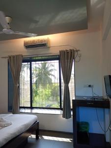 a bedroom with a window and a bed and a television at Alibag Beach Stay- The Grantley Hotel in Alibag