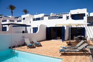 a house with a swimming pool with chairs and an umbrella at Villas Coloradas in Playa Blanca
