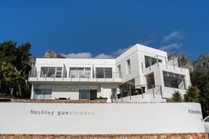 una casa blanca con montañas al fondo en Finchley Guesthouse in Camps Bay, en Ciudad del Cabo