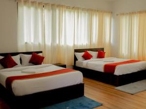 two beds in a room with white curtains and red pillows at Prakrithi Luxe Retreat in Padinjarathara +15 photos