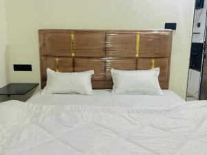 1 cama con 2 almohadas blancas y cabecero de madera en Ravrayhomestay, en Dholovira