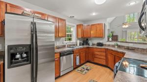 a kitchen with wooden cabinets and a stainless steel refrigerator at Chalet on Chalet by AvantStay Bright Cabin w Deck Fire Pit Near Lake in Lake Harmony +35 photos