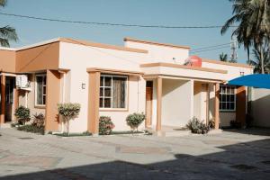 Una pequeña casa blanca con árboles delante. en Spine lobster, en Dar es Salaam