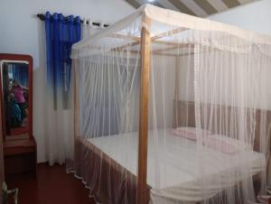 un lit à baldaquin avec des rideaux blancs dans une chambre dans l'établissement Bay Beach dom stay, à Tangalle