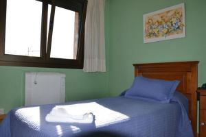 1 dormitorio con cama con sábanas azules y ventana en San Miguel de la Barreda, en Siero