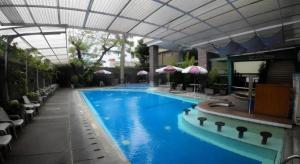 a large blue swimming pool with umbrellas in a building at Kedaton Hotel in Bandung